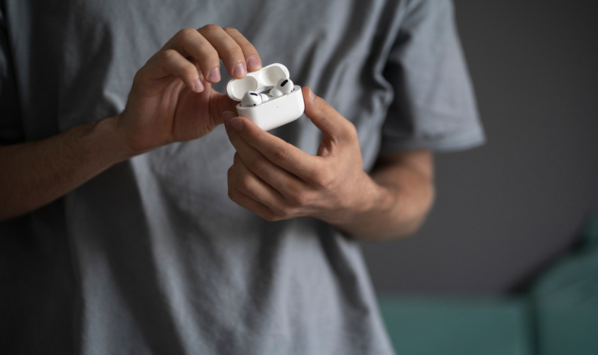 A man holding modern white earbuds.